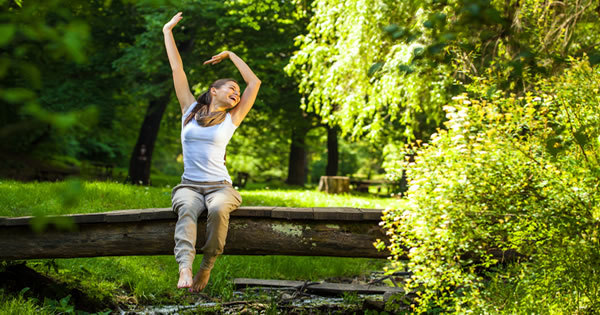 woman siting on a small bridge in nature