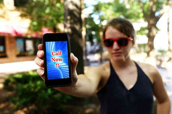 woman holding cellphone with message 'call now' displayed