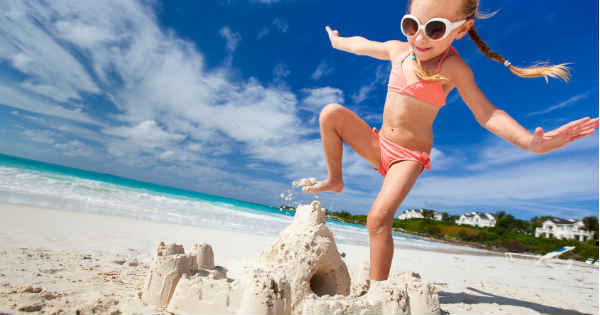 girl destroying a sand castle on the beach