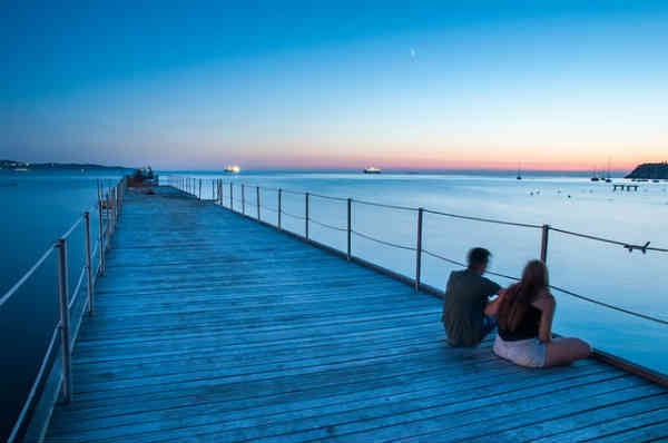 couple of friends talking sitting on a bridge