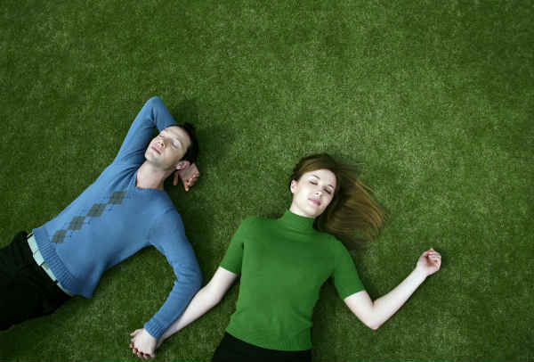 a couple lying on grass and holding hands