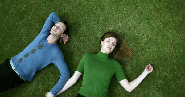 a couple laying on grass holding hands