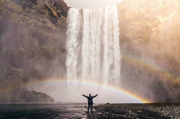 man standing in front of flowing waterfall