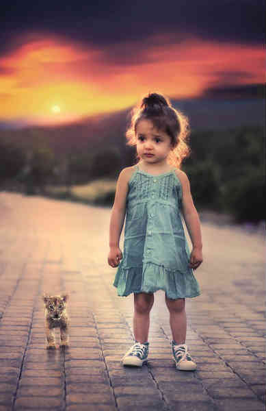 girl standing alongside lion cub