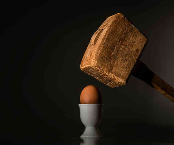 a wooden hammer is about to crush an egg