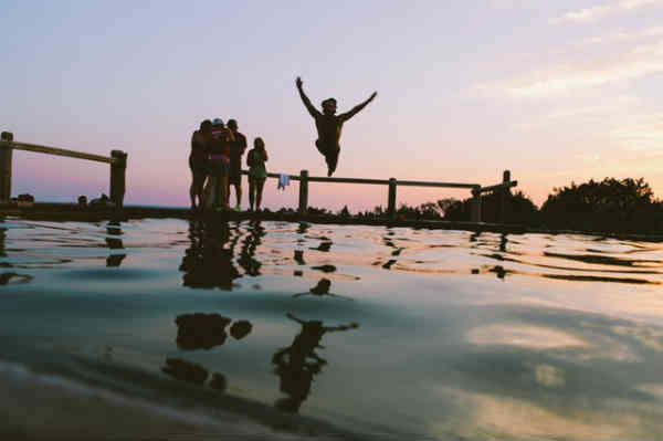 person jumping in water in front of friends