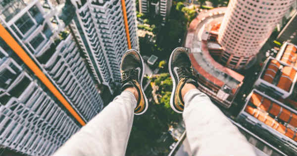 person's legs hanging from the top of a tall building
