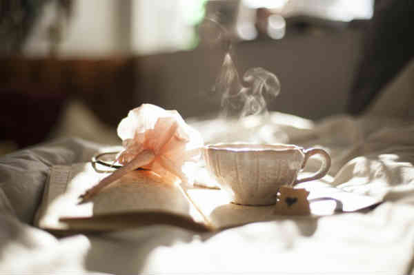 tea and journal on a bed