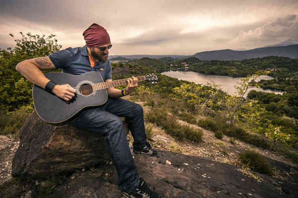 beardeed man playing a guitar in nature