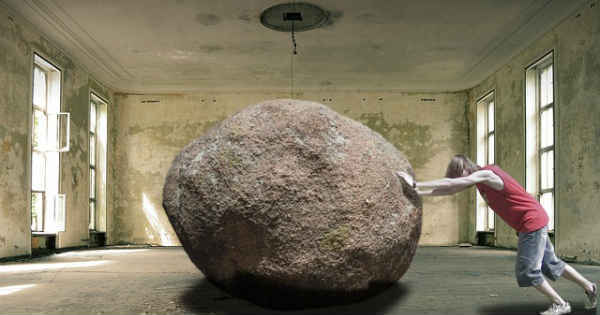 a man pushing a huge rock outside of his home