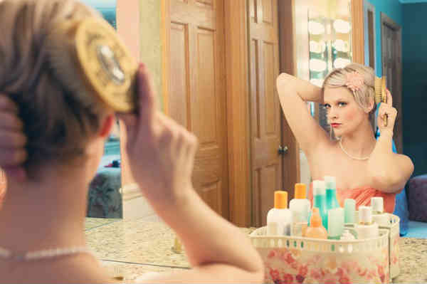 woman making herself pretty in front of mirror