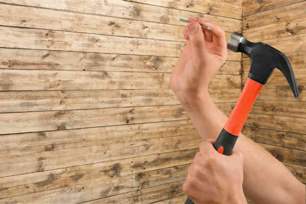 hammer drives a nail through a wall
