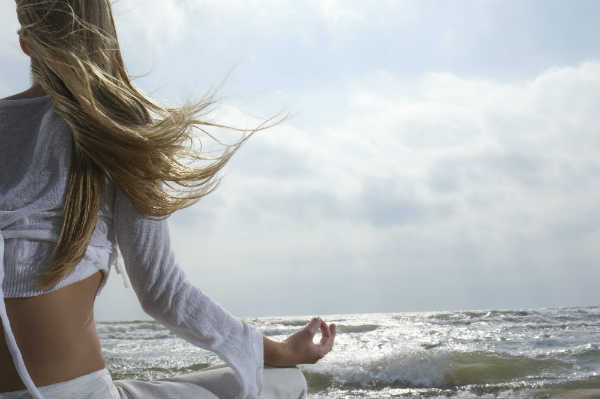 woman meditating on the beach