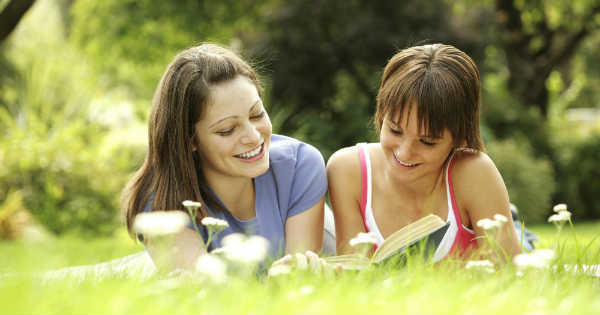 two friends relaxing in a park reading a book