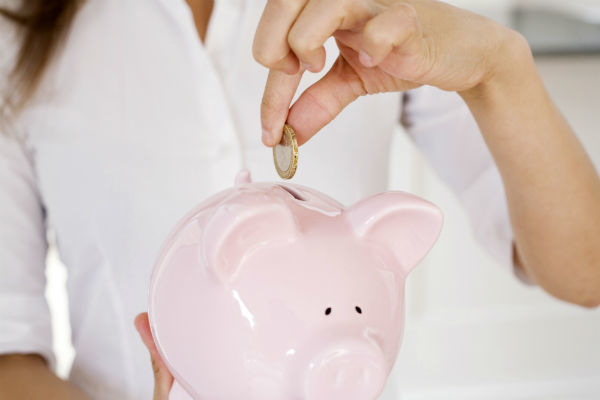 woman putting coins inside piggybank